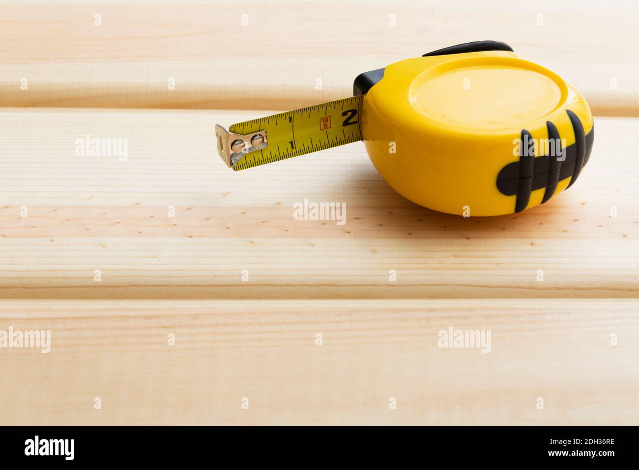 Maßband auf Holzoberfläche aufliegend, bereit für präzise Messungen in der Werkstattumgebung Stockfoto