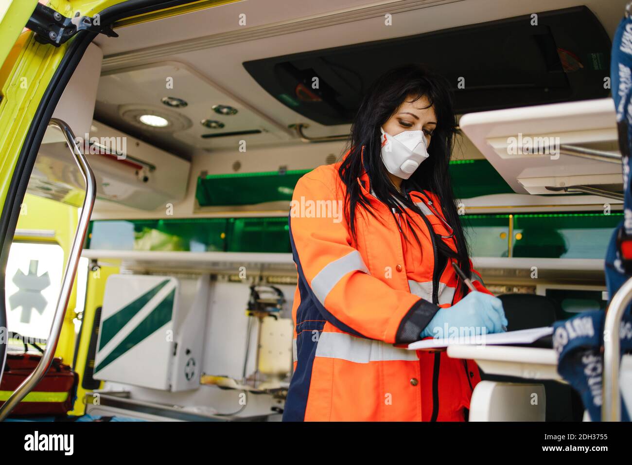 Junge weibliche Sanitäterin füllt Dokumente im Krankenwagen Stockfoto