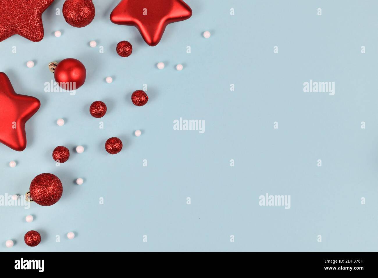 Rote Weihnachtsbaumkugeln in Form von Kugeln und Sternen Und weiße Schneeballornamente in der Ecke von hellblauem Hintergrund Mit leerem Kopierbereich Stockfoto