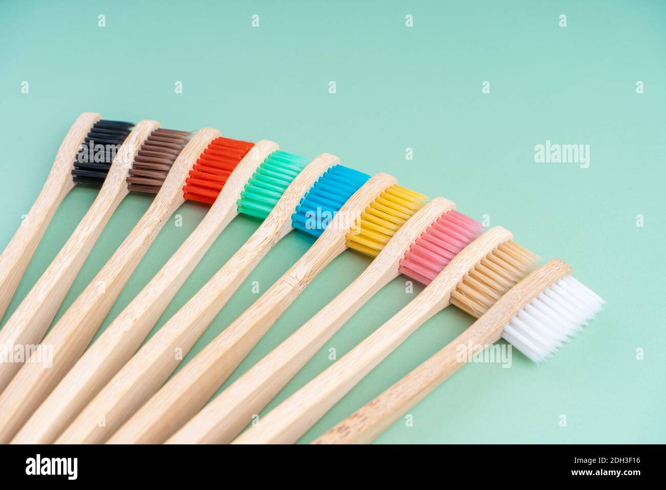 Ein Set umweltfreundlicher antibakterieller Zahnbürsten aus Bambusholz auf hellgrünem Hintergrund. Trends im Bereich Umweltschutz. Stockfoto