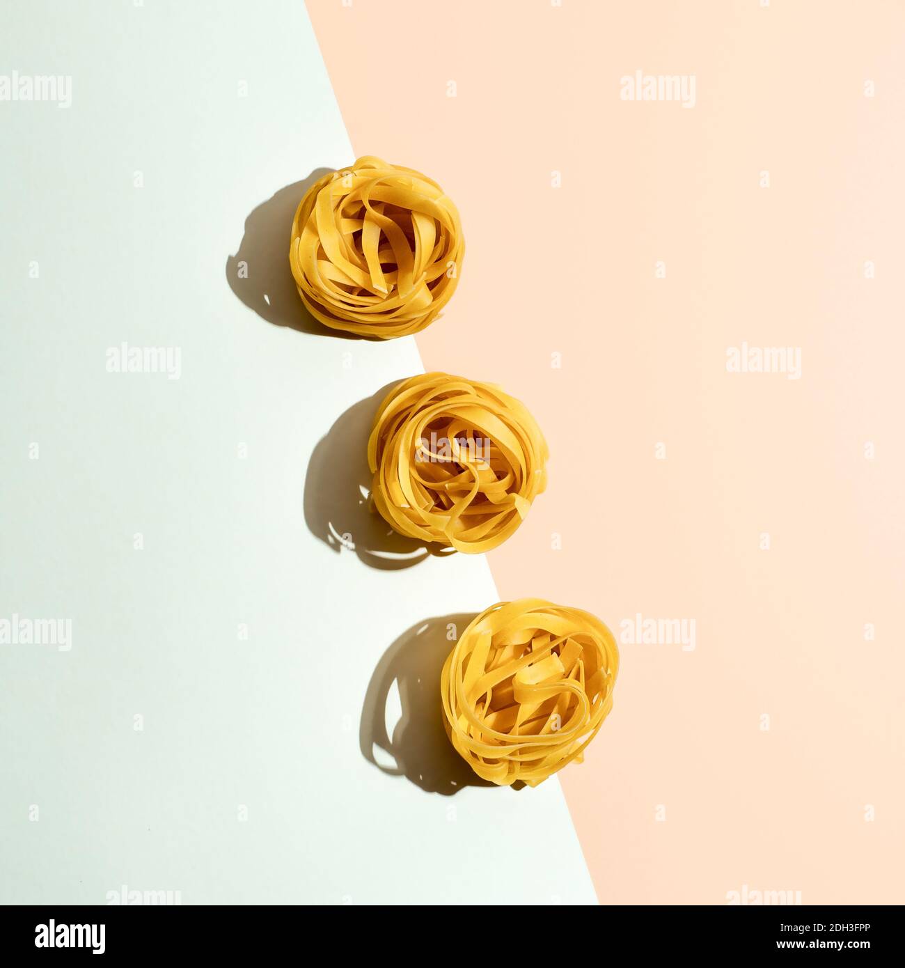 Pasta-Kunst mit Tagliatelle auf Pastellduoton Hintergrund Stockfoto