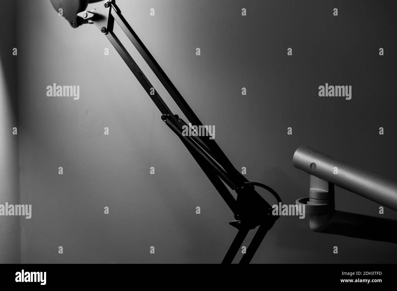 Schwarz-weiß monochromes Bild der artikulierten Schreibtischlampe mit Schwarze Arme im Vordergrund verwischen und mit Leuchtmittel beleuchtet Mit seinem Schatten an der Wand.A Stockfoto Schwarz-weiß monochromes Bild der artikulierten Schreibtischlampe mit Schwarze Arme im Vordergrund verwischen und mit Leuchtmittel beleuchtet Mit seinem Schatten an der Wand.A Stockfoto