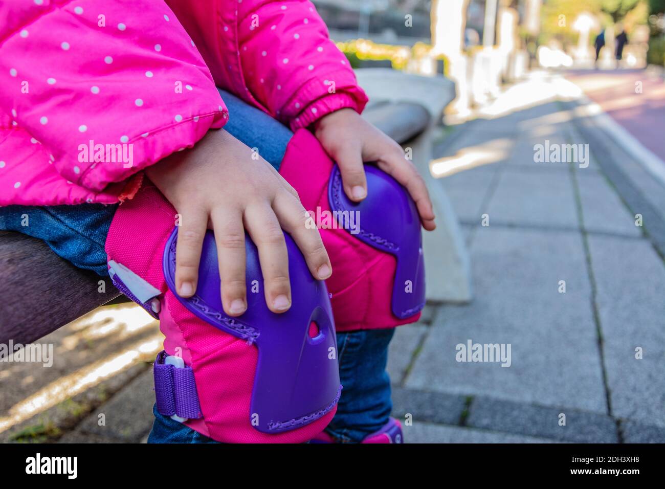 Unkenntlich kleines Mädchen hält ihre Kniepolster, während sie sitzt Die Bank Stockfoto