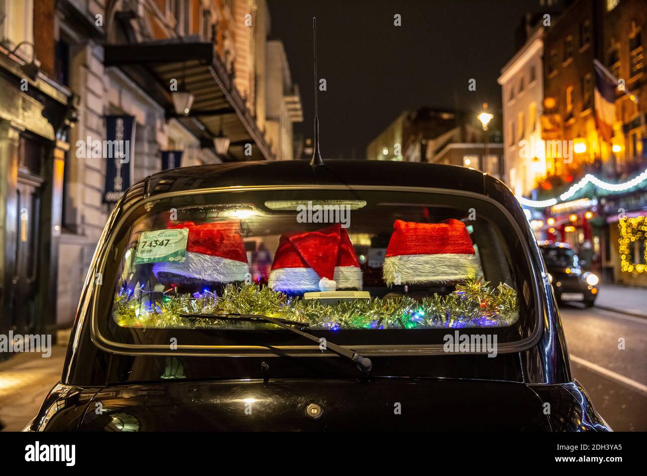 Ein rückes Taxi mit festlichen Weihnachtsmützen, die das hintere Fenster schmücken, sitzt in Covent Garden, London, England, Großbritannien Stockfoto
