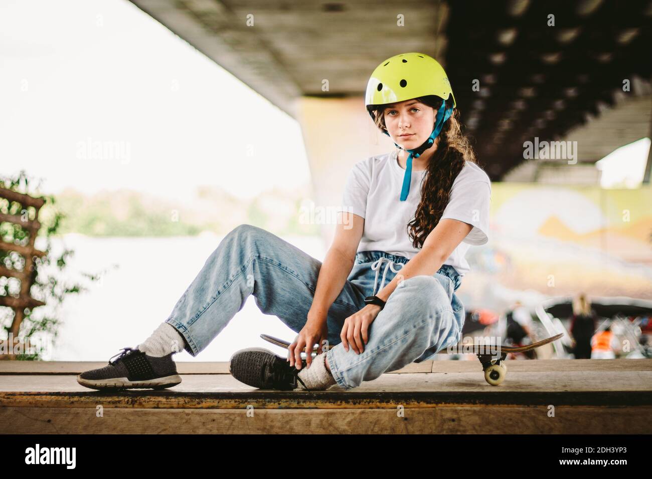 Portrait selbstbewusste, coole junge Skateboarderin im Outdoor Skatepark. Urban Mädchen mit Skate-Board auf Halfpipe Rampe. Lifesty Stockfoto