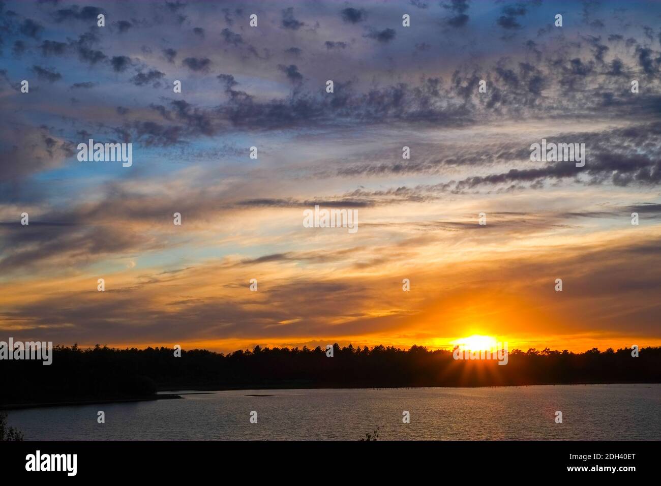 Dramatischer Sonnenuntergang über einem Waldsee Stockfoto