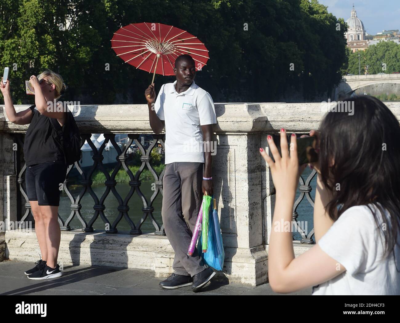 KEIN WEB/KEINE APPS - EIN junger Migrant aus Senegal verkauft am 24. Juli 2017 Regenschirme an Touristen auf einer Brücke im Zentrum Roms. Die meisten afrikanischen Migranten haben die Aufnahmezentren verlassen, um einige Tage vor ihrer Weiterreise nach Norden hier zu bleiben, einige wissen nicht, dass die Grenzen für sie geschlossen sind, andere sind entschlossen, es nach gescheiterten Überquerung erneut zu versuchen. Jeder hier hat Wochen, Monate oder sogar Jahre auf der Straße verbracht, Trekking durch die Wüste, durch Libyen und über das Mittelmeer. Foto von Eric Vandeville/ABACAPRESS.COM Stockfoto