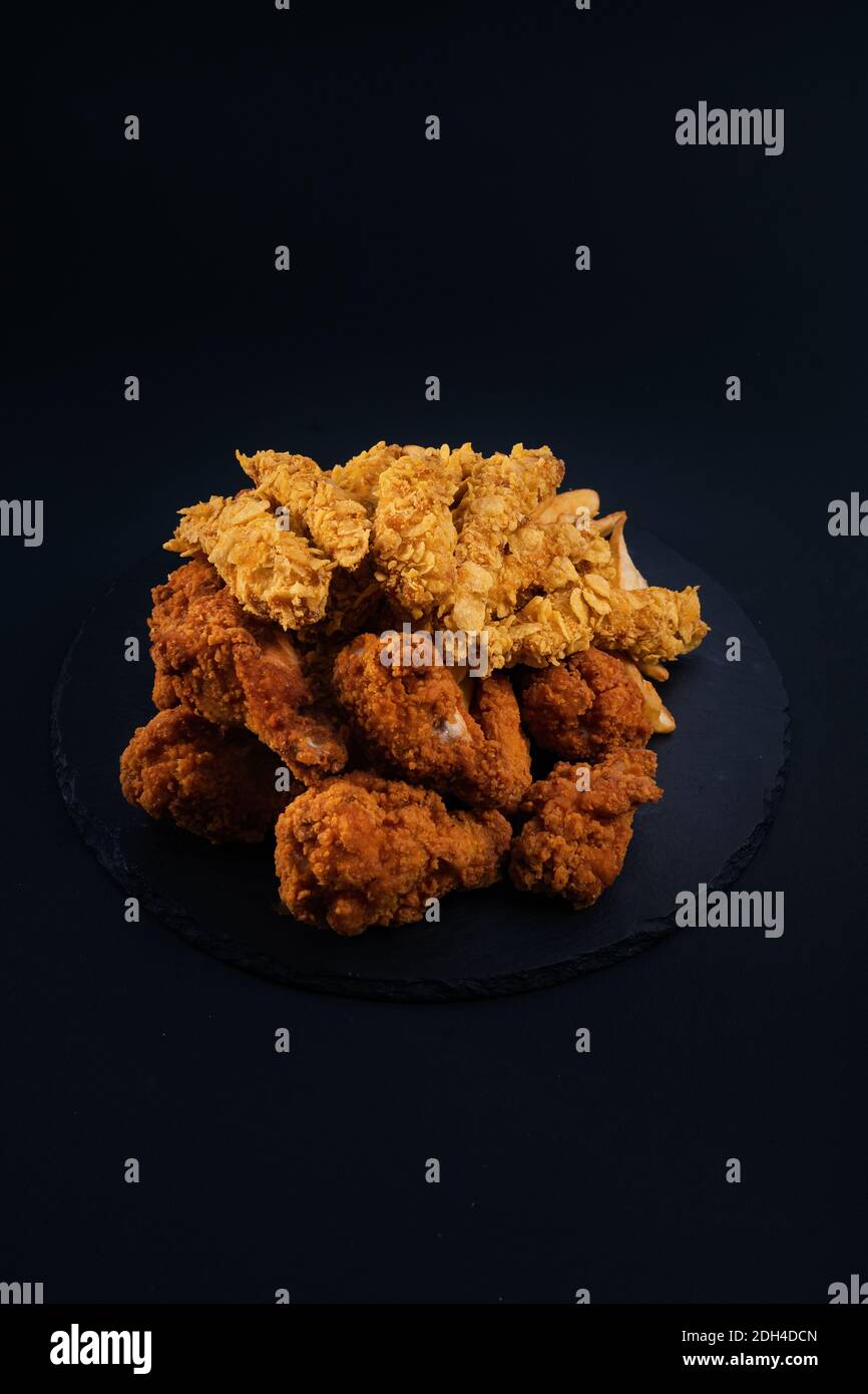 Eine Nahaufnahme eines schwarzen Serviertellers voller Hähnchennuggets und knusprig gebratenes Huhn Stockfoto