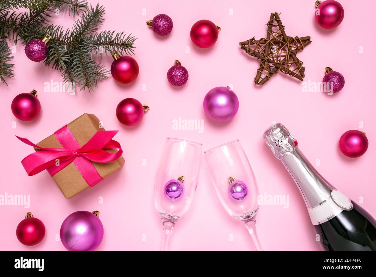 Weihnachtsschmuck, Champagner, Tannenbaum und Geschenkbox auf pastellrosa Hintergrund. Das Konzept der Feier des neuen Jahres und Weihnachten. Draufsicht. Stockfoto