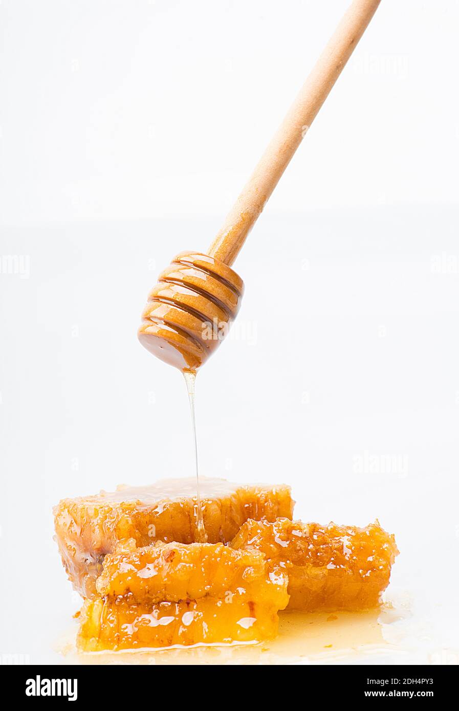 Spezieller Honiglöffel, der Honig auf eine Honigwabe tropft Stockfoto
