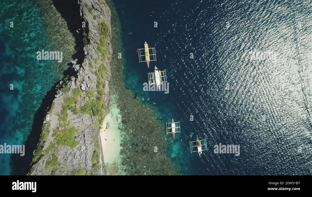 Passagierboote am seichten Wasser der Ozeanbucht von oben nach unten aus der Luft. Filmische Sommerferien Landschaft von Kreuzfahrt auf Schiffen auf den Philippinen Archipel Inseln. Epische Seestück mit Sonnenreflexion Stockfoto