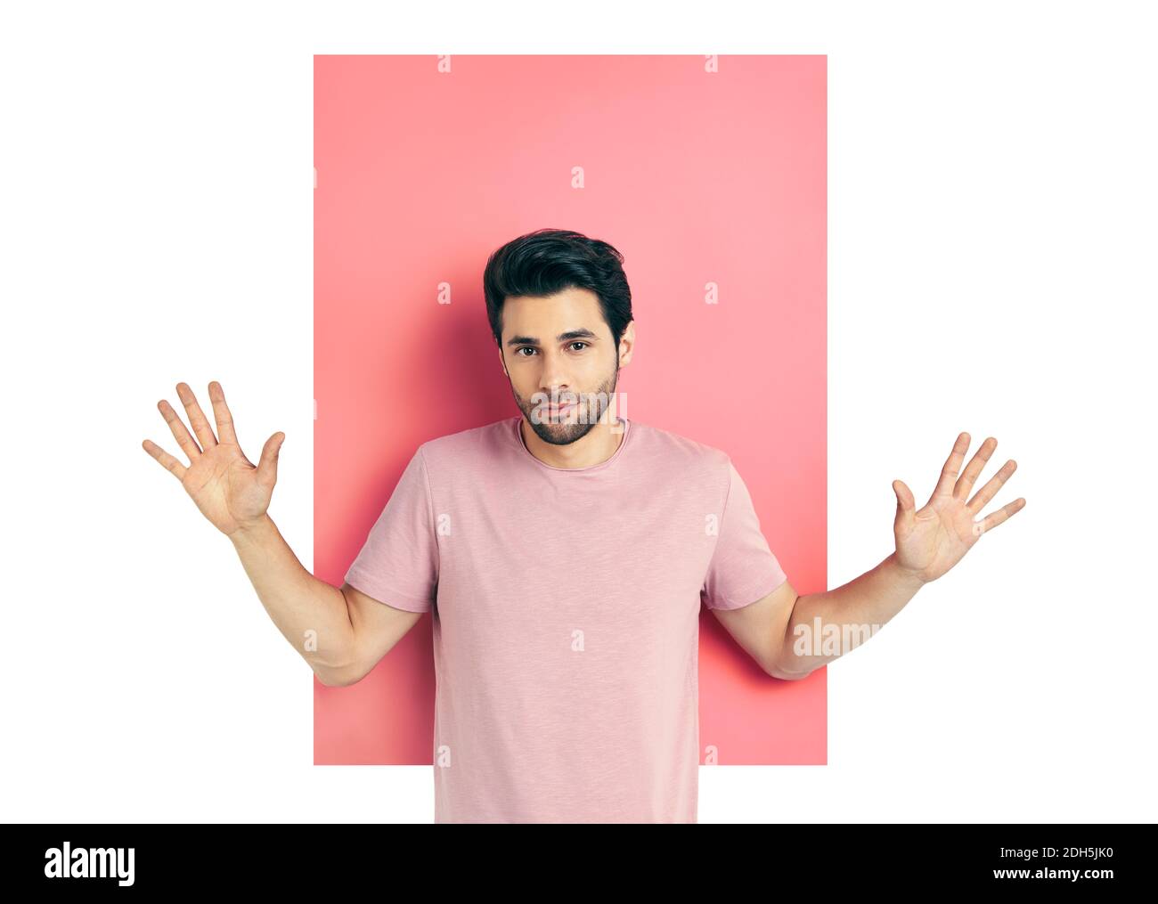 Überrascht junger Mann mit den Armen nach oben in der Kamera über rosa und weißen Hintergrund erstaunt schauen. Stockfoto