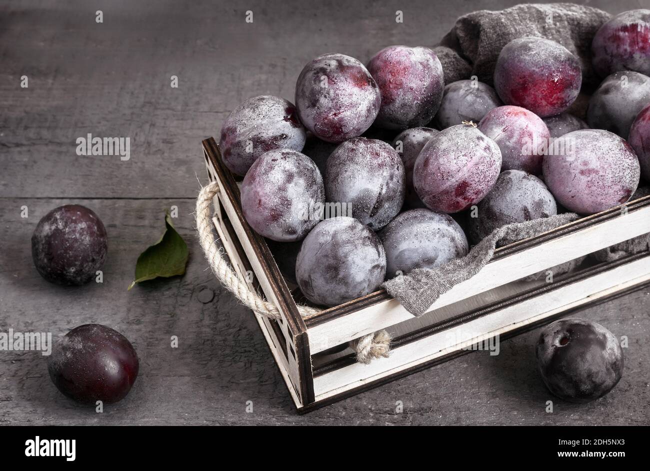 Große reife Pflaumen in einem Behälter auf dem Tisch Stockfoto