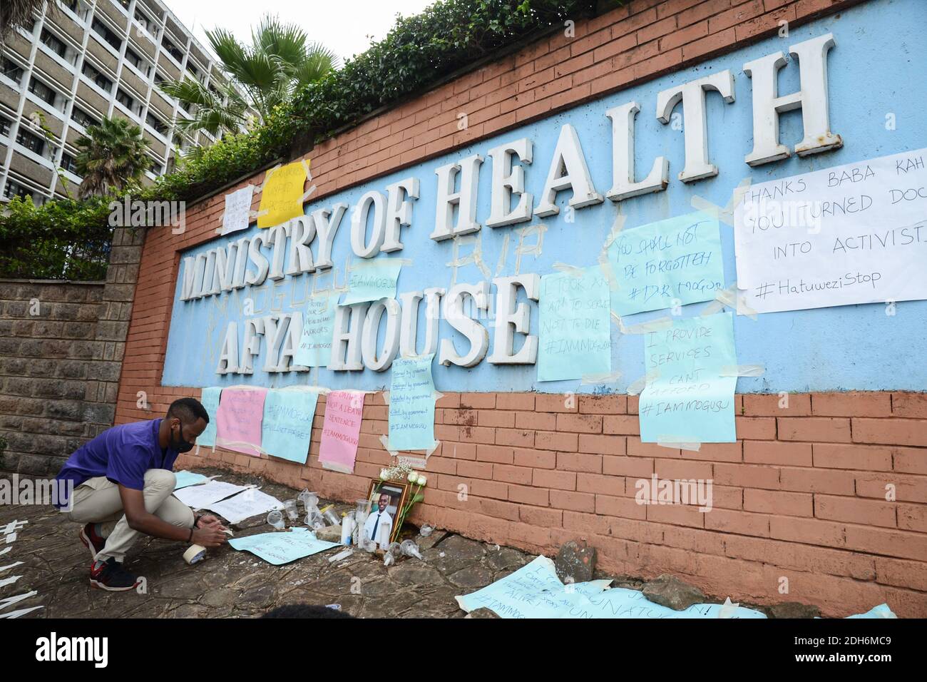 Nairobi, Kenia. Dezember 2020. Ein Protestant zündet während der Demonstration eine Kerze neben dem Porträt ihres Kollegen an.Beschäftigte im Gesundheitswesen protestieren vor dem Hauptquartier des Gesundheitsministeriums, um einen ihrer Kollegen, Dr. Stephen Mogusu, zu ehren, einen 28-jährigen medizinischen Mitarbeiter, der dem Coronavirus erlag und über schlechte Arbeitsbedingungen, fehlende PPEs (Persönliche Schutzausrüstung) und Nichtbezahlung von Risikozulagen für ihre Kollegen, die sich während dieser COVID-19-Periode an vorderster Front befinden. Kredit: SOPA Images Limited/Alamy Live Nachrichten Stockfoto