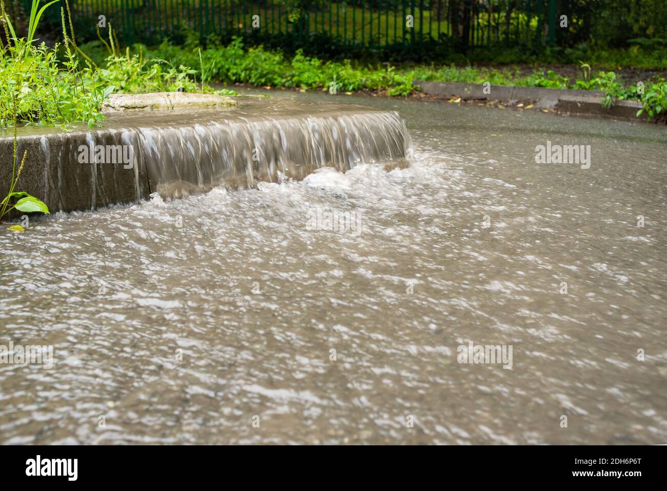 Der Wasserstrom fließt hinunter in die Fußgängerzone. Regnerisches Herbstwetter. Starker Regen. Straßenszenen im Regen. Stockfoto