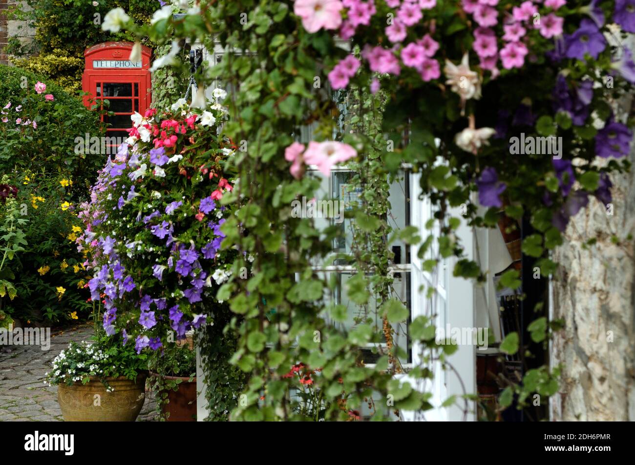 Rote Telefonzelle mit Blumen an der Wand Stockfoto