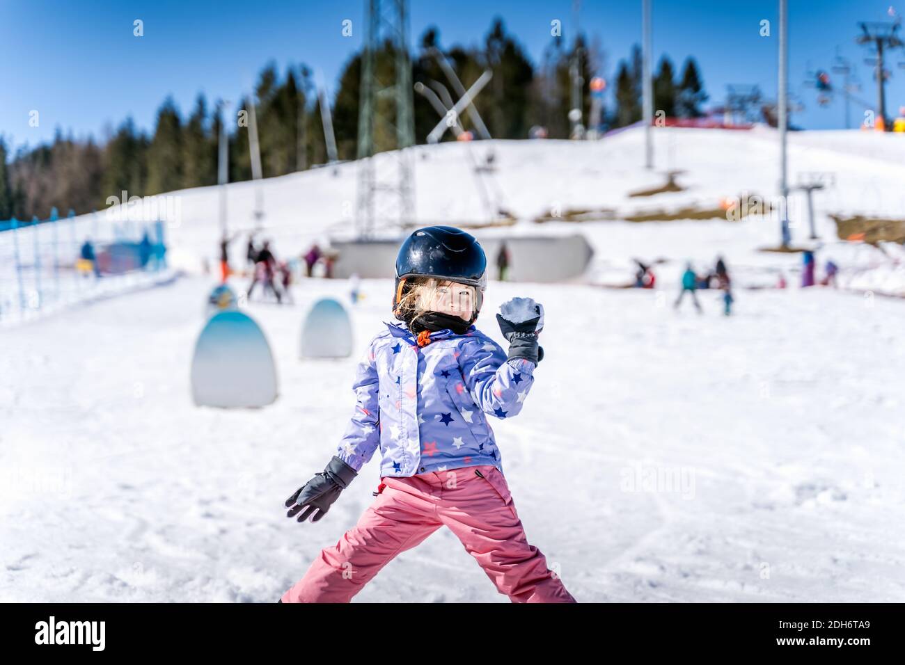 Junge glückliche Skifahrer Mädchen Schneebälle in Schneeballschlacht werfen. Stockfoto