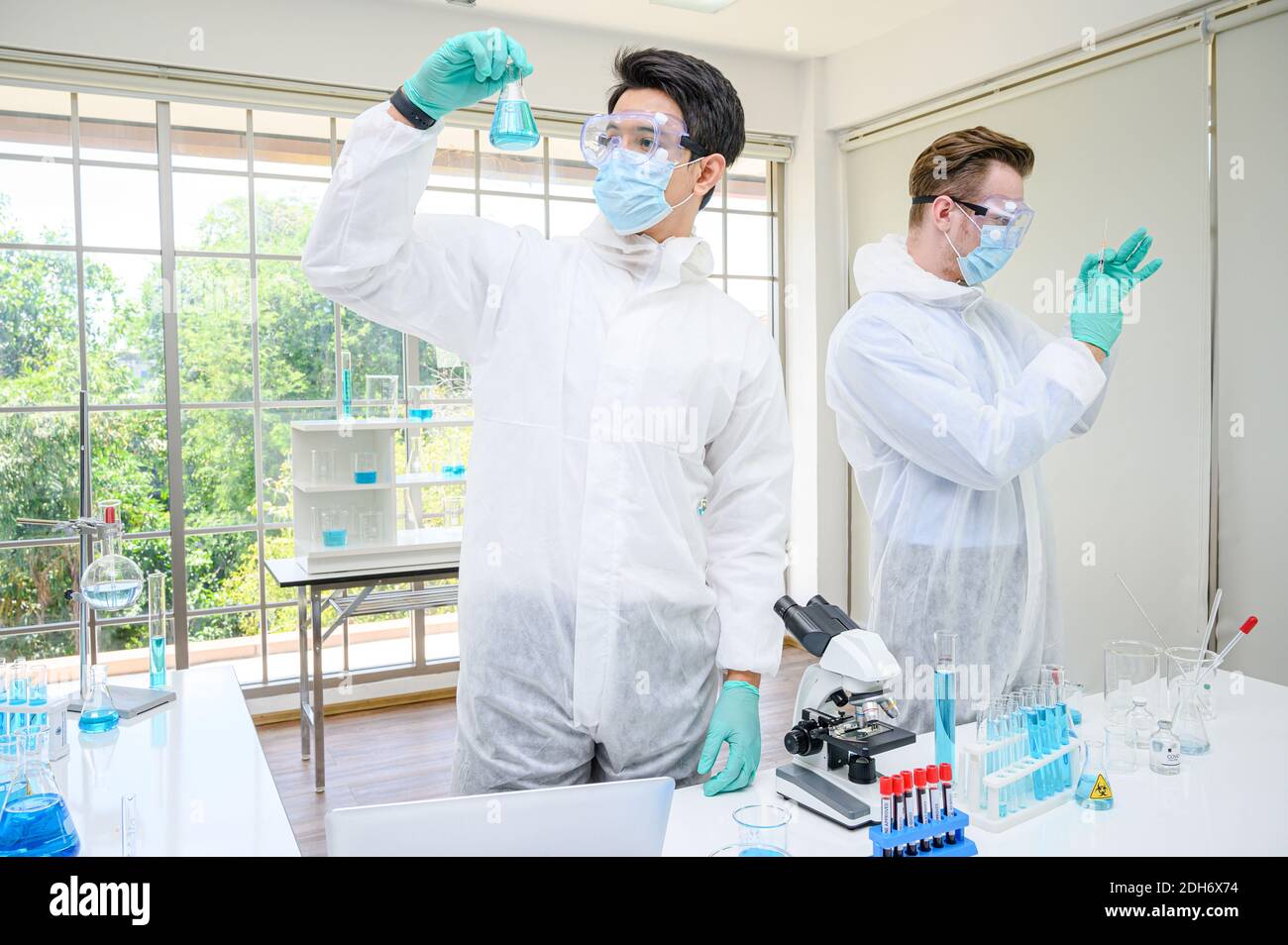 Paar männlichen Wissenschaftler tragen Schutzanzug mit Coronavirus-Impfstoff und die Arbeit mit vielen Laborgeräten für Forschung Impfstoff im Labor. Viru Stockfoto