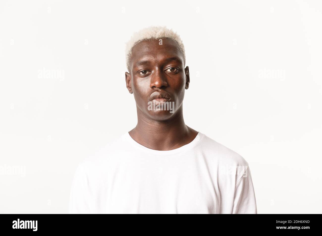 Nahaufnahme von seriösen schönen afroamerikanischen blonden stilvollen Kerl, Blick auf die Kamera entschlossen und ruhig, stehend weiß backgroun Stockfoto