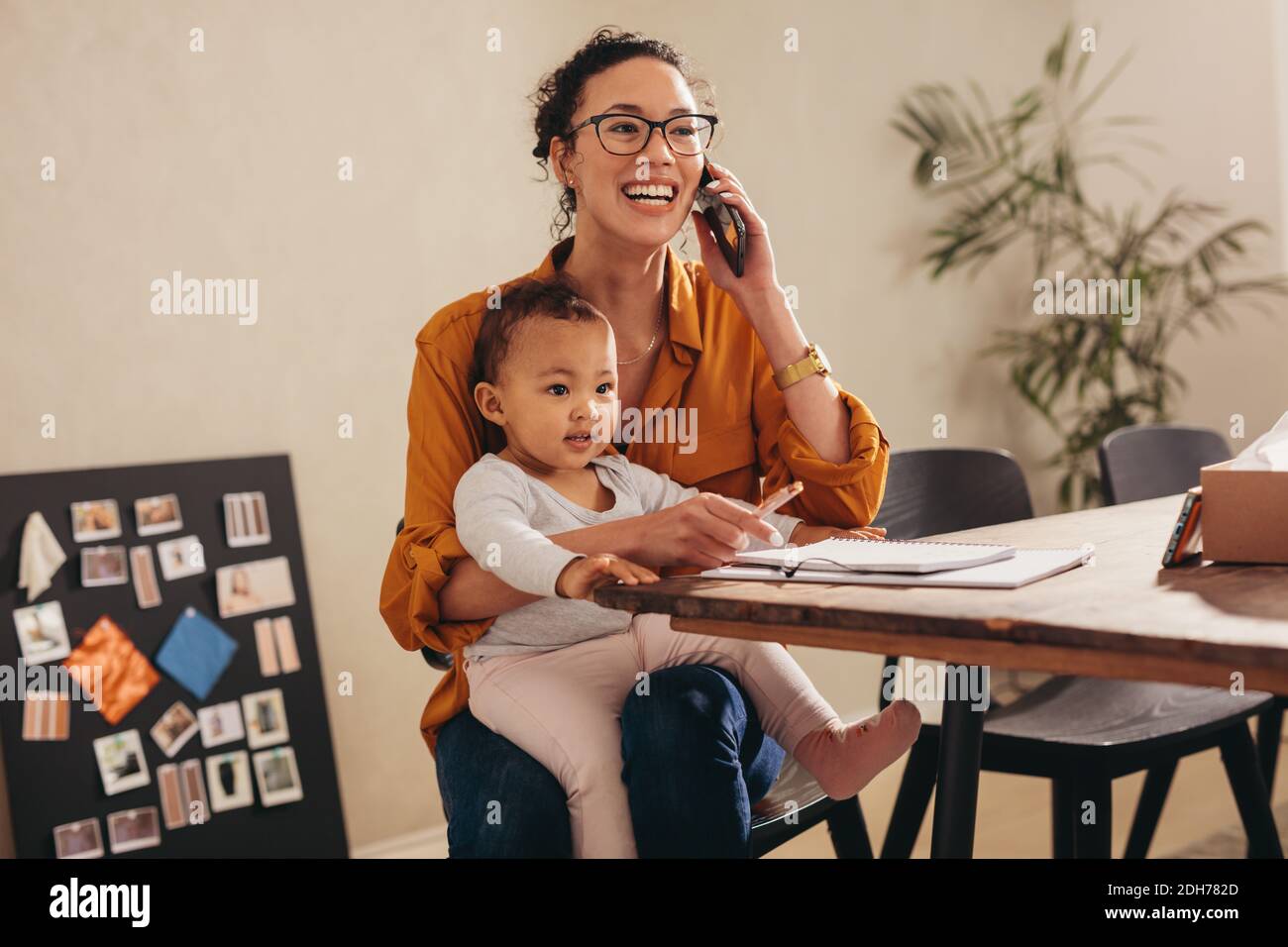 Frau mit ihrem Baby im Gespräch mit einem Kunden während der Arbeit von zu Hause aus. Arbeiten Mama Handling ihr Geschäft von zu Hause aus. Stockfoto