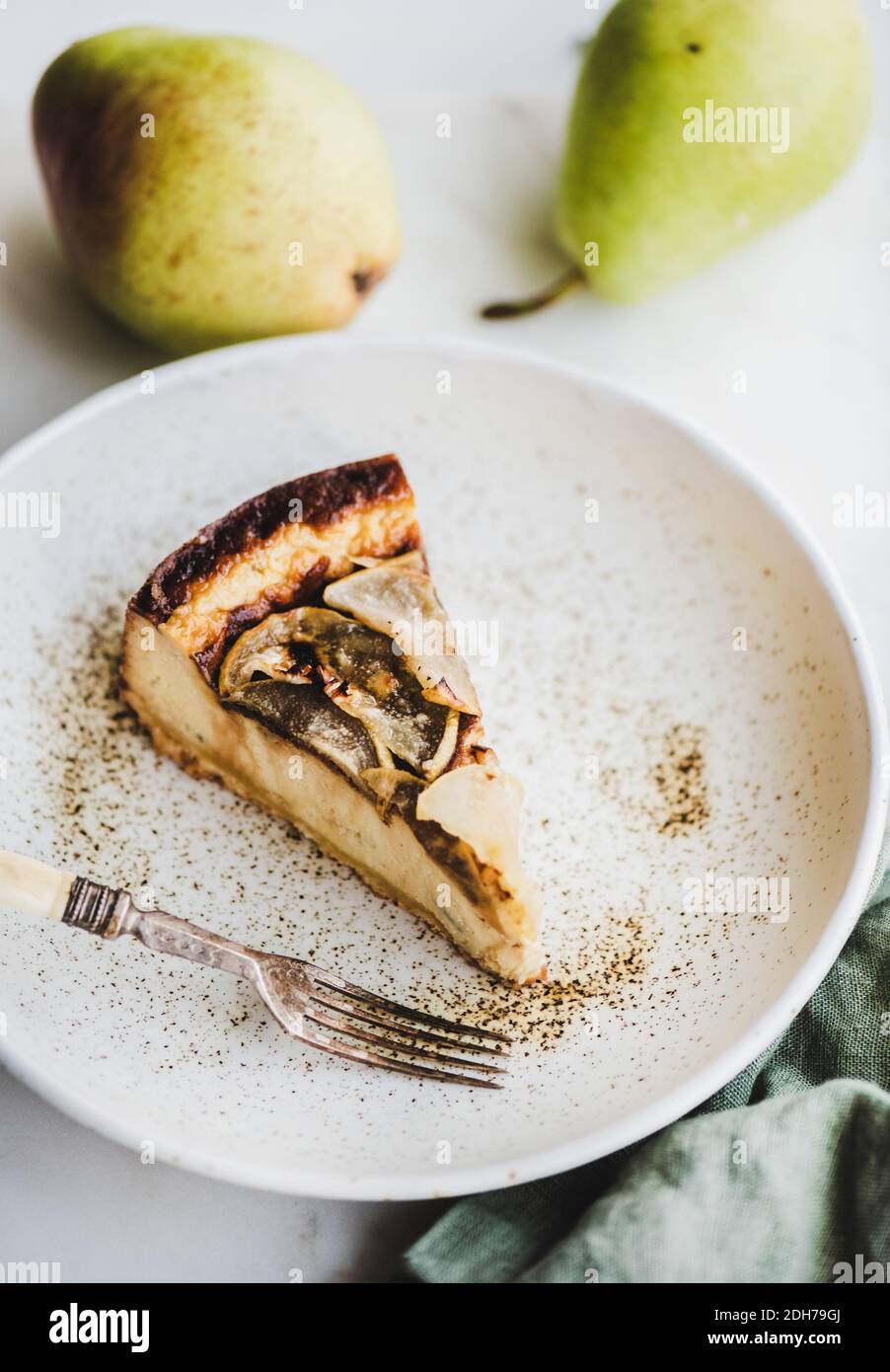 Stück vegan milchfrei zuckerfreier Birne Käsekuchen in rustikalem Teller über weißem Marmortisch Hintergrund, Draufsicht. Modernes vegetarisches gesundes Dessertkonzept Stockfoto