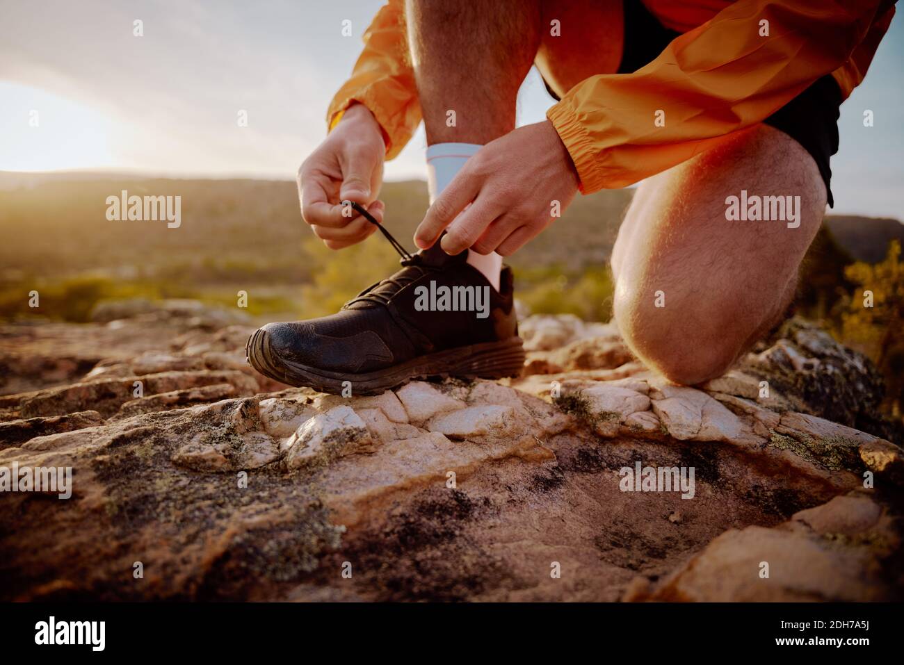 Nahaufnahme der Hände von fit männlichen Jogger Binden Schnürsenkel Vorbereitung Für Langlauf Bergweg in der Natur bei Sonnenaufgang laufen Stockfoto