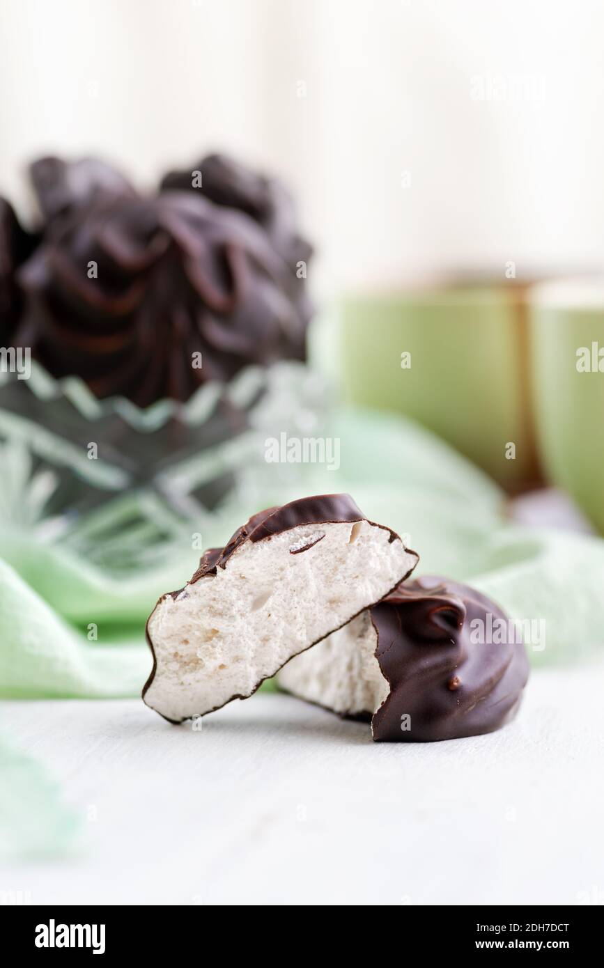 Weiße russische Marshmallow in Schokolade in Schale auf einem Holztisch. Das Stillleben, selektive Fokus. Vertikal Stockfoto