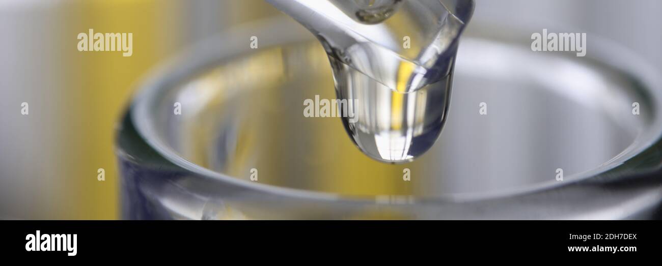 Chemischer Pipettenspender tropft gelbe Flüssigkeit in die Glaswaren in der Nähe Stockfoto