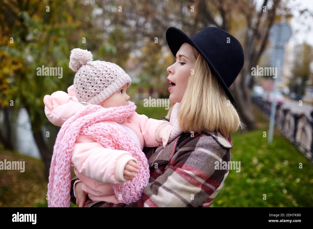 Schöne Baby-Mädchen mit Mutter im Freien. Familien im Freien. Liebenswert kleines Mädchen in warmen Kleidern im Herbst Park an sonnigen Tag. Hübsches kleines Mädchen mit Mo Stockfoto