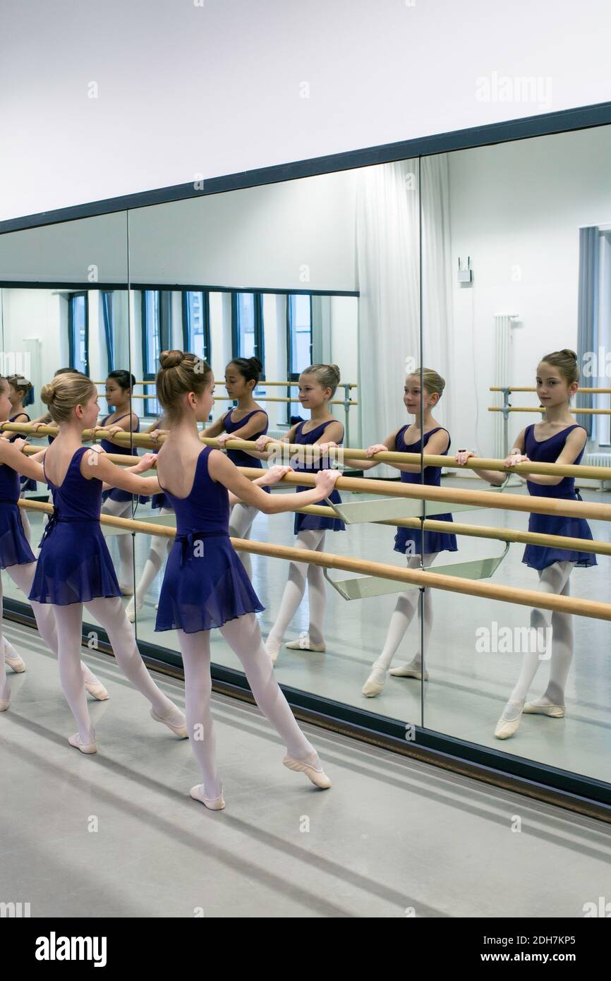 Kleine Ballerinas mit Barre beim Üben im Tanzstudio.Ballerinas sind alle für den Unterricht in passenden Trikots, Strumpfhosen und Ballettschuhen gekleidet. Stockfoto