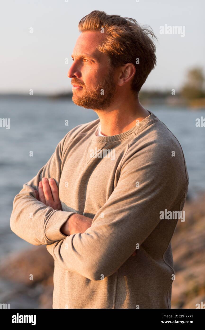 Nachdenklicher Mann, der Arme am Strand kreuzt Stockfoto