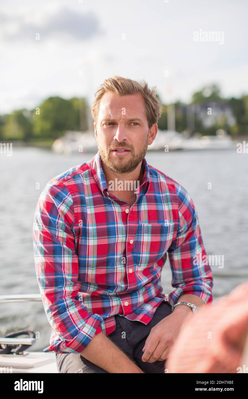 Mittelerwachsener Mann, der auf der Yacht am Fluss sitzt Stockfoto Mittelerwachsener Mann, der auf der Yacht am Fluss sitzt Stockfoto