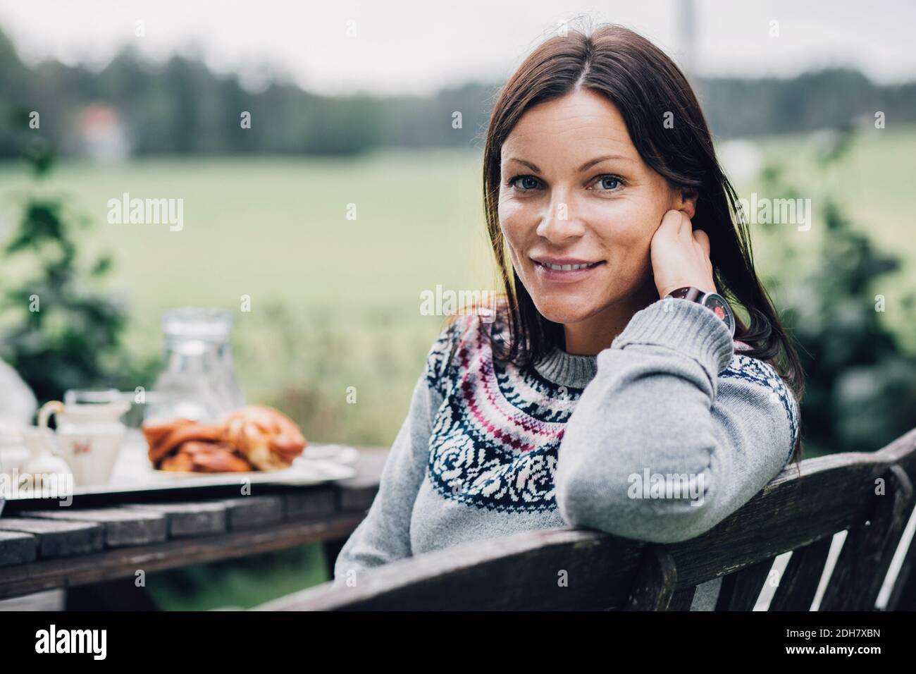 Portrait einer lächelnden Frau, die am Frühstückstisch in Bio sitzt Bauernhof Stockfoto