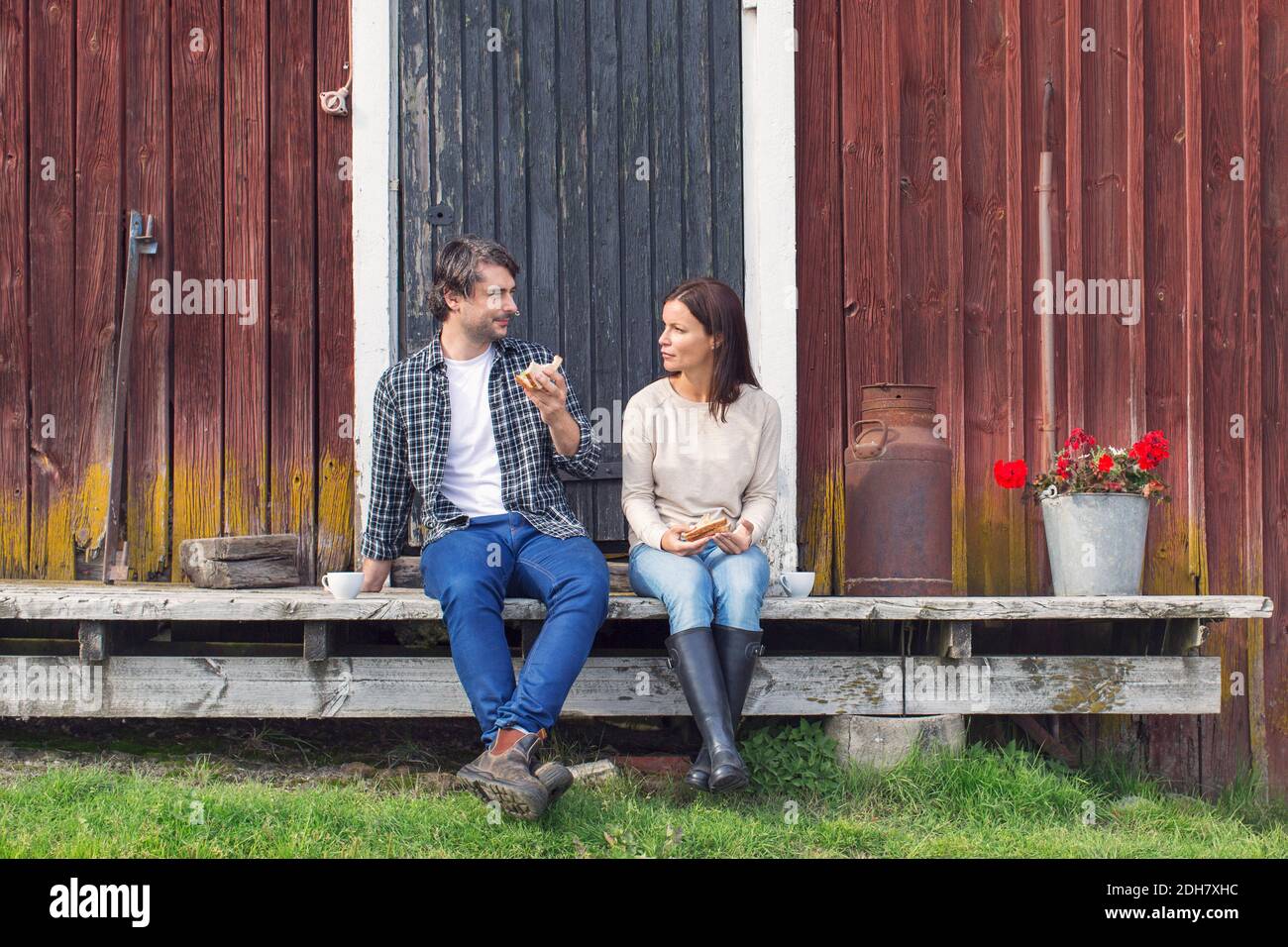 Pärchen beim Frühstück, während sie draußen auf der Scheune sitzen Stockfoto