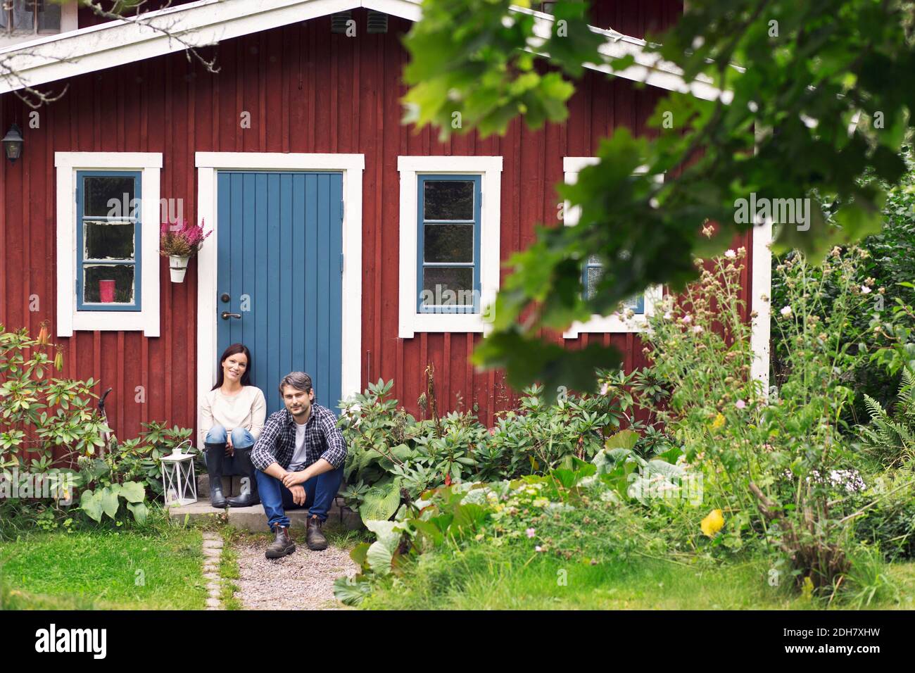 Mittelerwachsenes Paar, das außerhalb des Bauernhauses sitzt Stockfoto