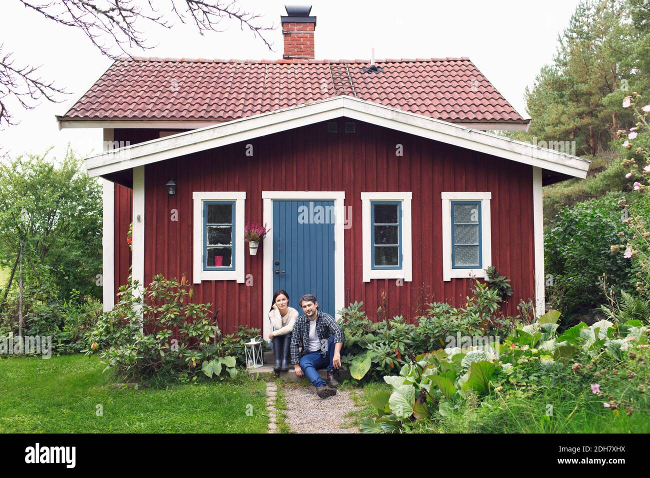 Mittelerwachsenes Paar, das außerhalb des Bauernhauses sitzt Stockfoto