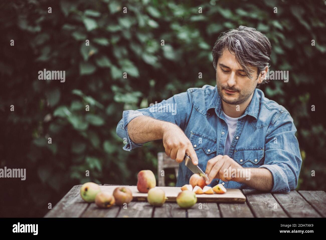 Mittlerer Erwachsener Mann schneidet Äpfel am Tisch in Bio-Bauernhof Stockfoto Mittlerer Erwachsener Mann schneidet Äpfel am Tisch in Bio-Bauernhof Stockfoto