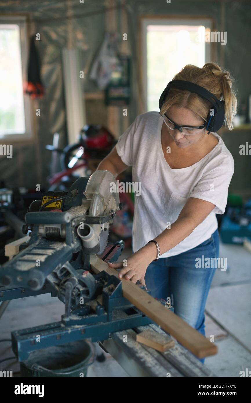 Frau schneidet Holz mit Kreissäge während der Heimwerker Stockfoto