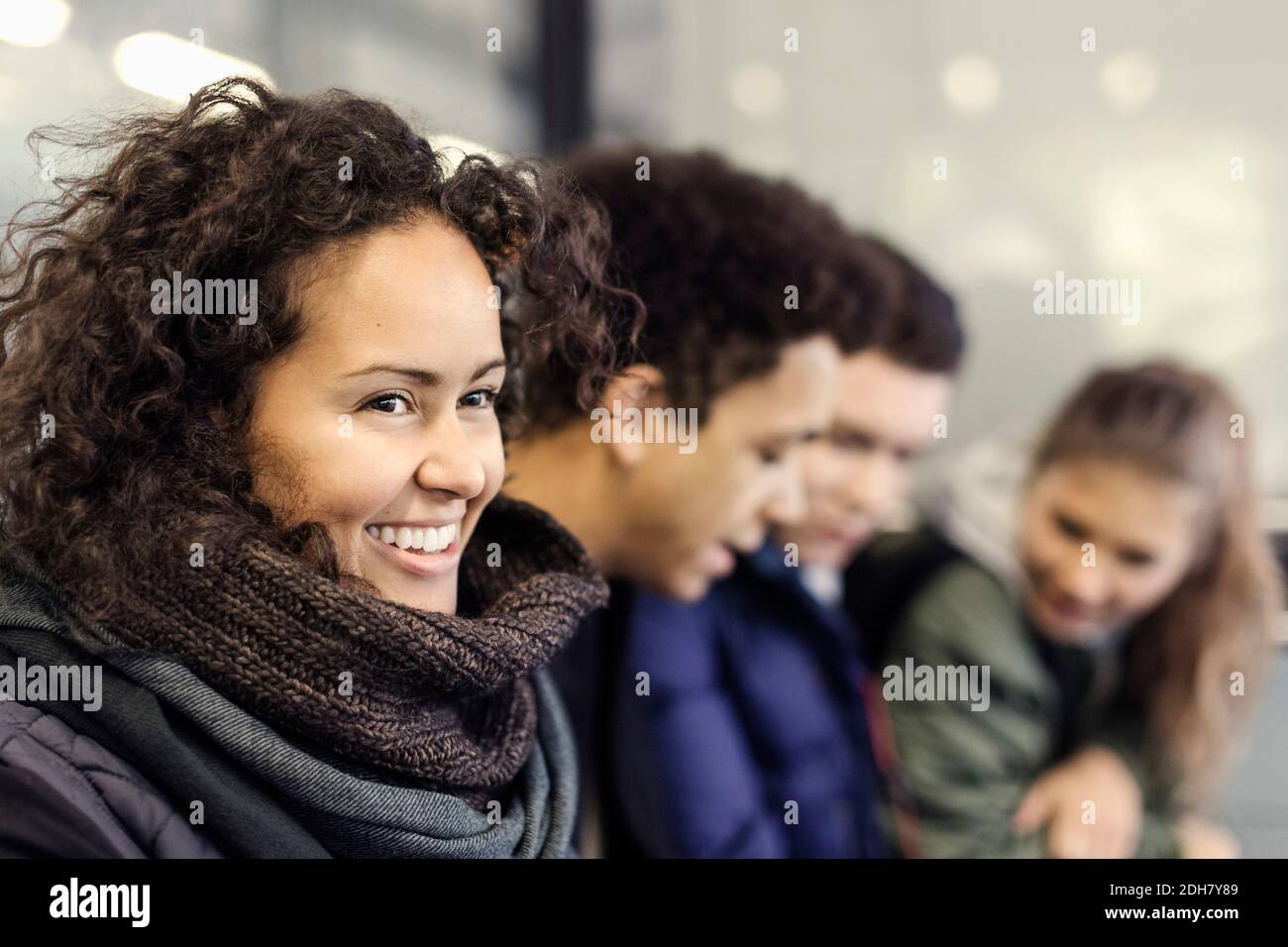 Glücklicher Universitätsstudent, der mit Freunden an der U-Bahn-Station sitzt Stockfoto