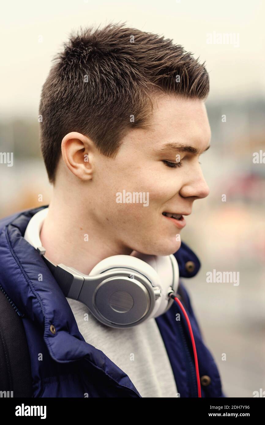 Lächelnder Student der Universität mit Kopfhörern um den Hals im Freien Stockfoto