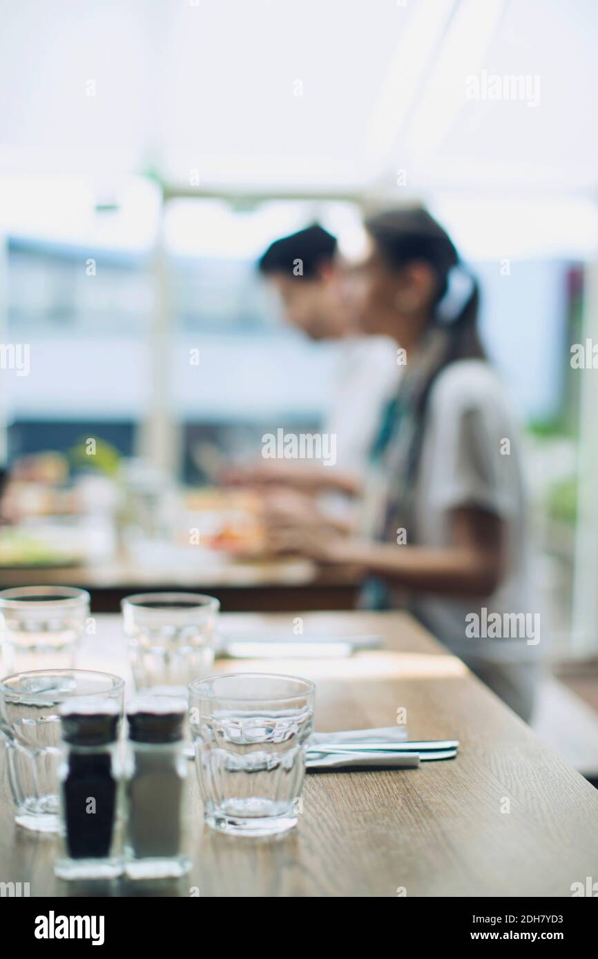 Trinkgläser mit Salz- und Pfefferstreuer auf dem Tisch mit Paar im Hintergrund Stockfoto