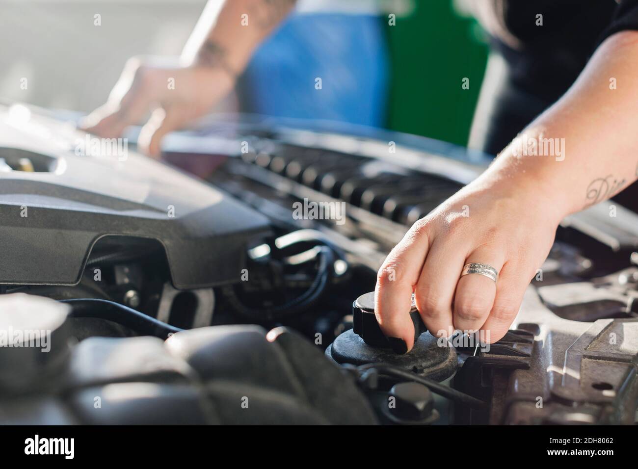 Zugeschnittenes Bild einer Mechanikerin, die Kühlmittel im Auto öffnet Stockfoto