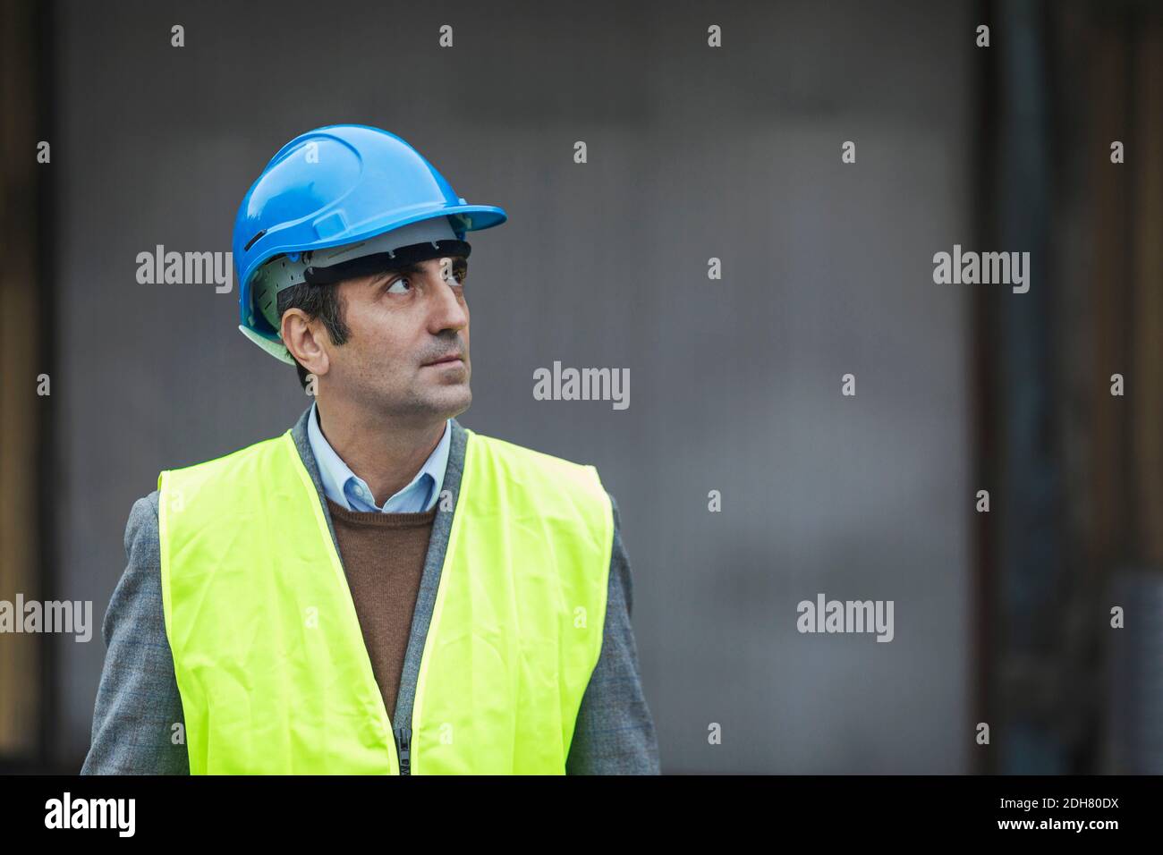 Reifer Arbeiter mit schützender Arbeitskleidung, der in die Fabrik schaut Stockfoto