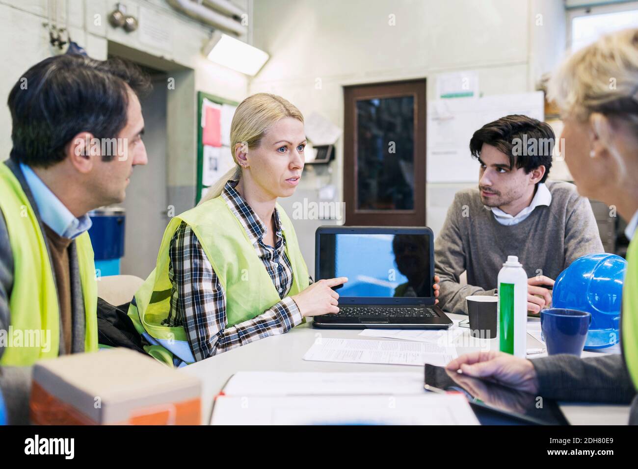 Arbeiterin zeigt Kollegen im Werk etwas auf dem Laptop Stockfoto
