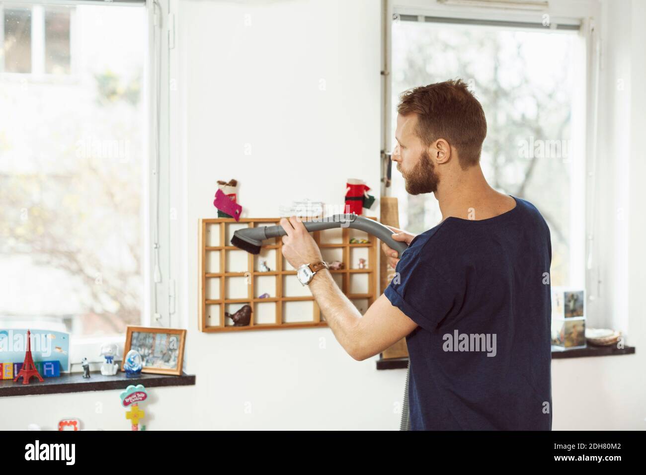 Junger Mann saugt kleine Regale zu Hause Stockfoto