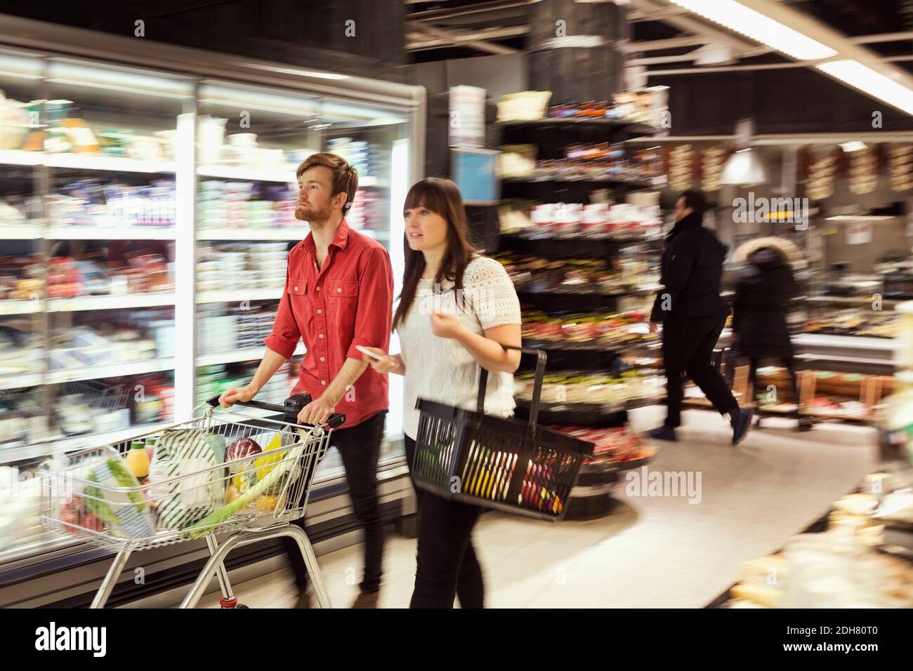 Junges Paar mit Lebensmitteln zu Fuß im Supermarkt Stockfoto