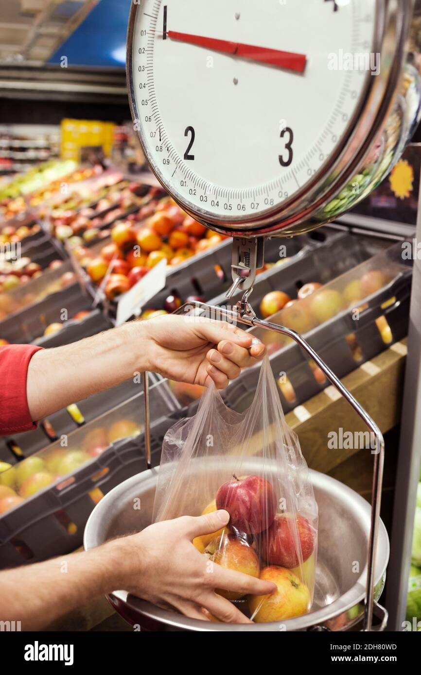Zugeschnittenes Bild eines Mannes, der im Supermarkt Äpfel wägt Stockfoto