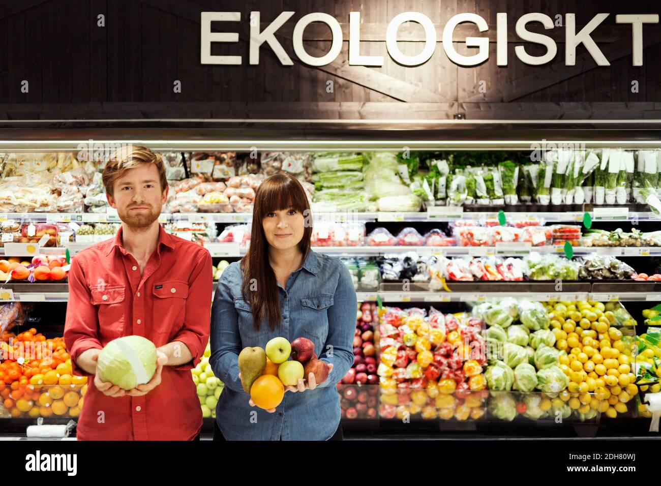 Portrait eines jungen Paares, das frisches Gemüse im Supermarkt hält Stockfoto