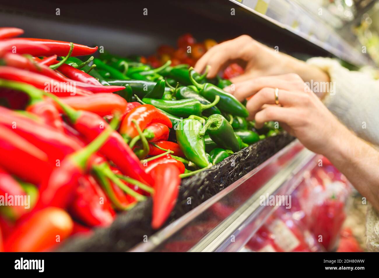 Zugeschnittenes Bild des Mannes, der Chilischoten im Supermarkt kauft Stockfoto