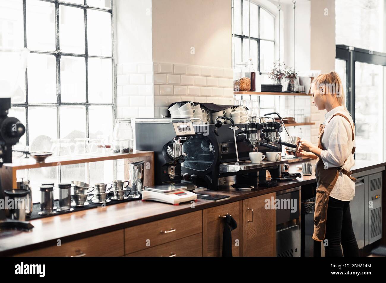 Weibliche Barista, die die Kaffeemaschine im Café benutzt Stockfoto